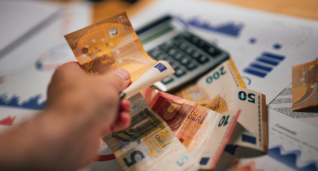 Gros plan de billets en euros sur des documents financiers et une calculatrice, illustrant la planification financière.
