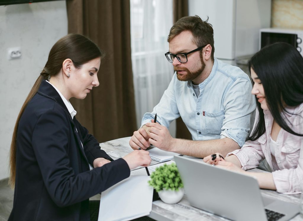 Un couple discute de documents financiers avec leur conseiller, mettant en avant des stratégies d'investissement.