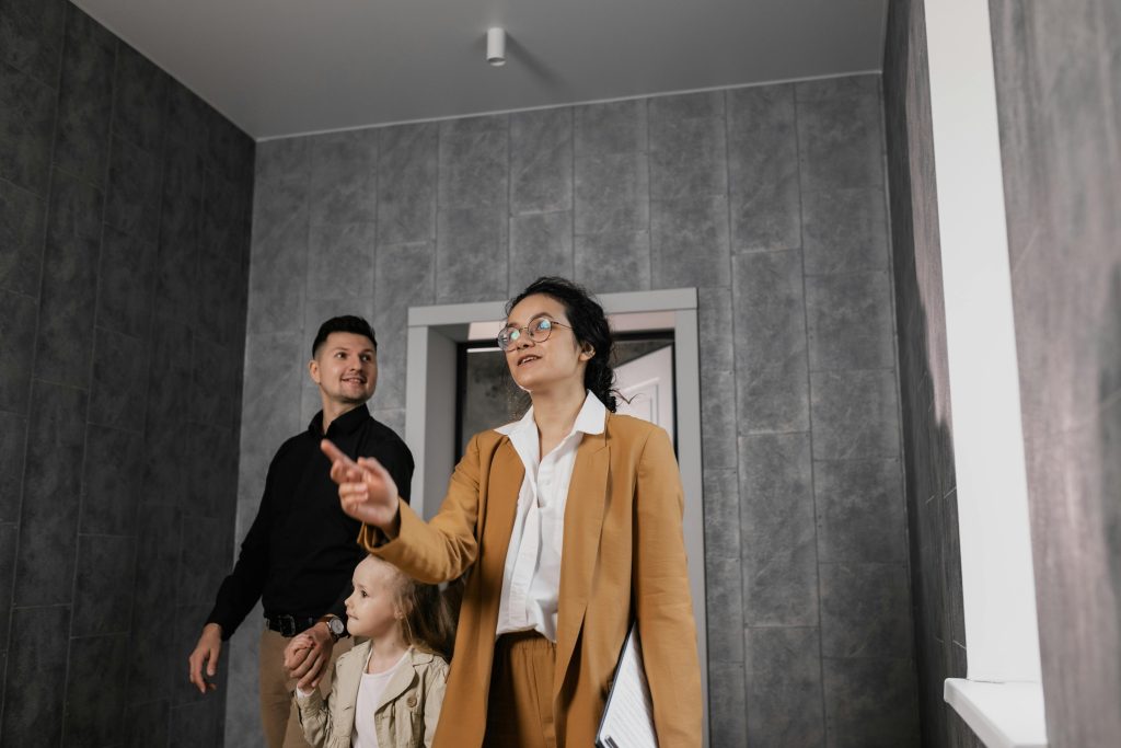A family explores a modern home interior with a professional realtor guiding them. Une famille explore l'intérieur d'une maison moderne avec un agent immobilier professionnel qui les guide.