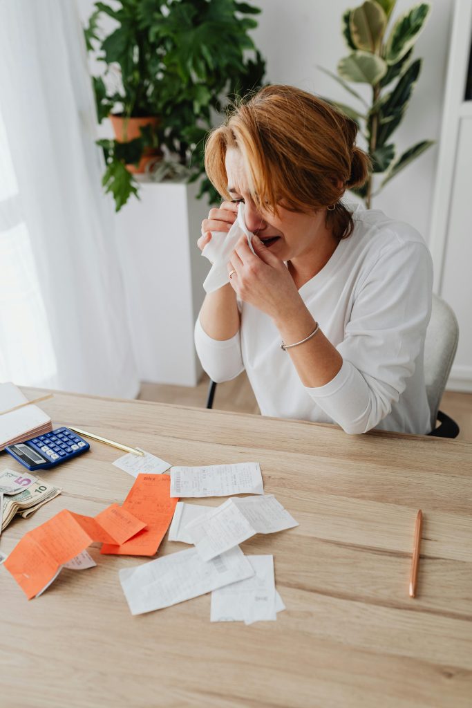 Stressed woman calculant des dépenses et des dettes avec des reçus et des factures à la maison