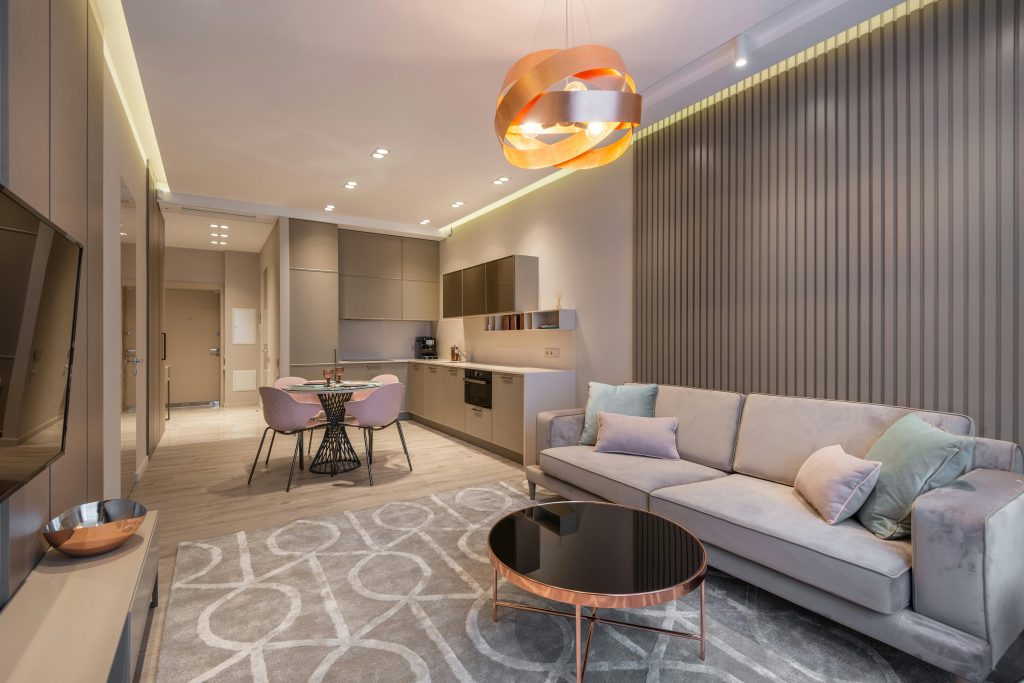 Canapé confortable et table basse ronde près de la zone cuisine décorée d'un lustre créatif dans un appartement contemporain