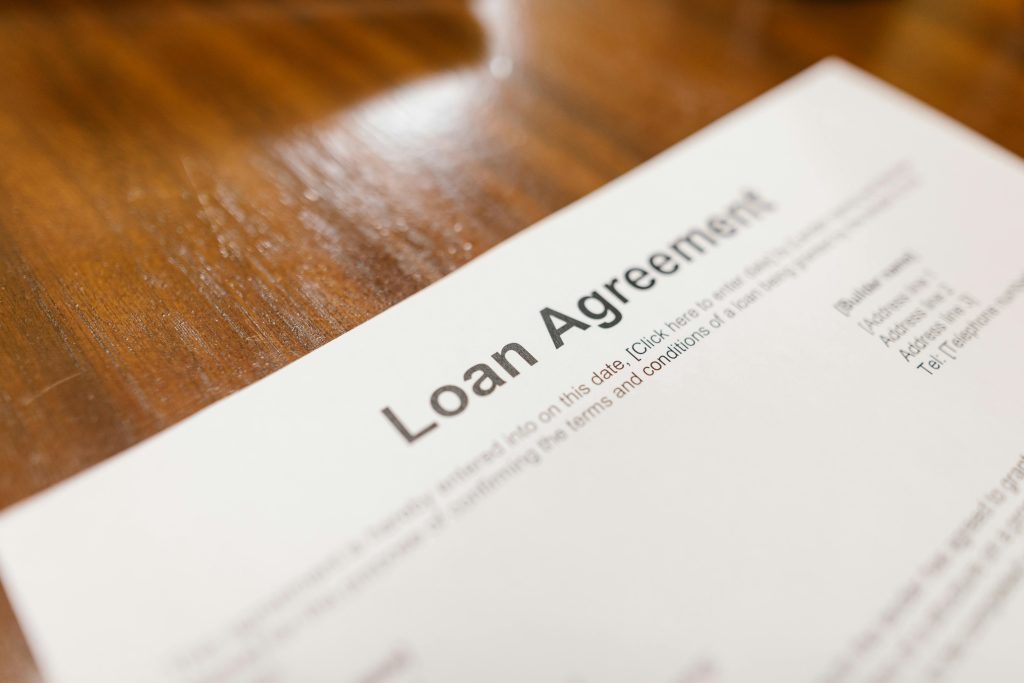 Detailed loan agreement document close-up on a wooden table representing legal and financial concepts. Document de prêt détaillé en gros plan sur une table en bois représentant des concepts juridiques et financiers.
