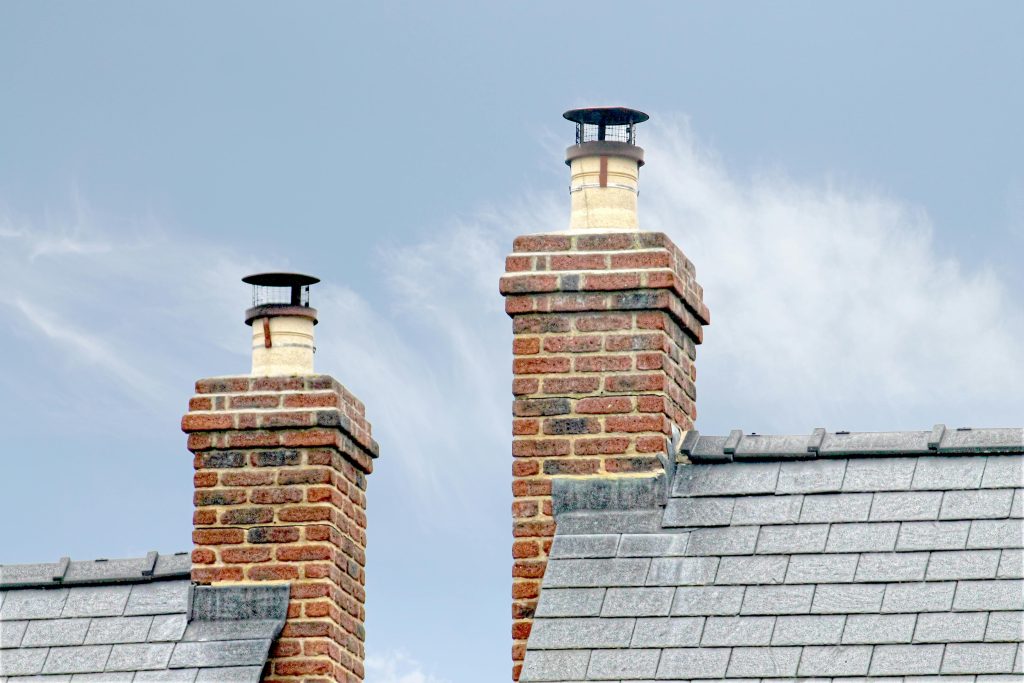 Close-up of traditional brick chimneys on a slate roof, England. Gros plan sur les cheminées en brique traditionnelles sur un toit d'ardoise, Angleterre.