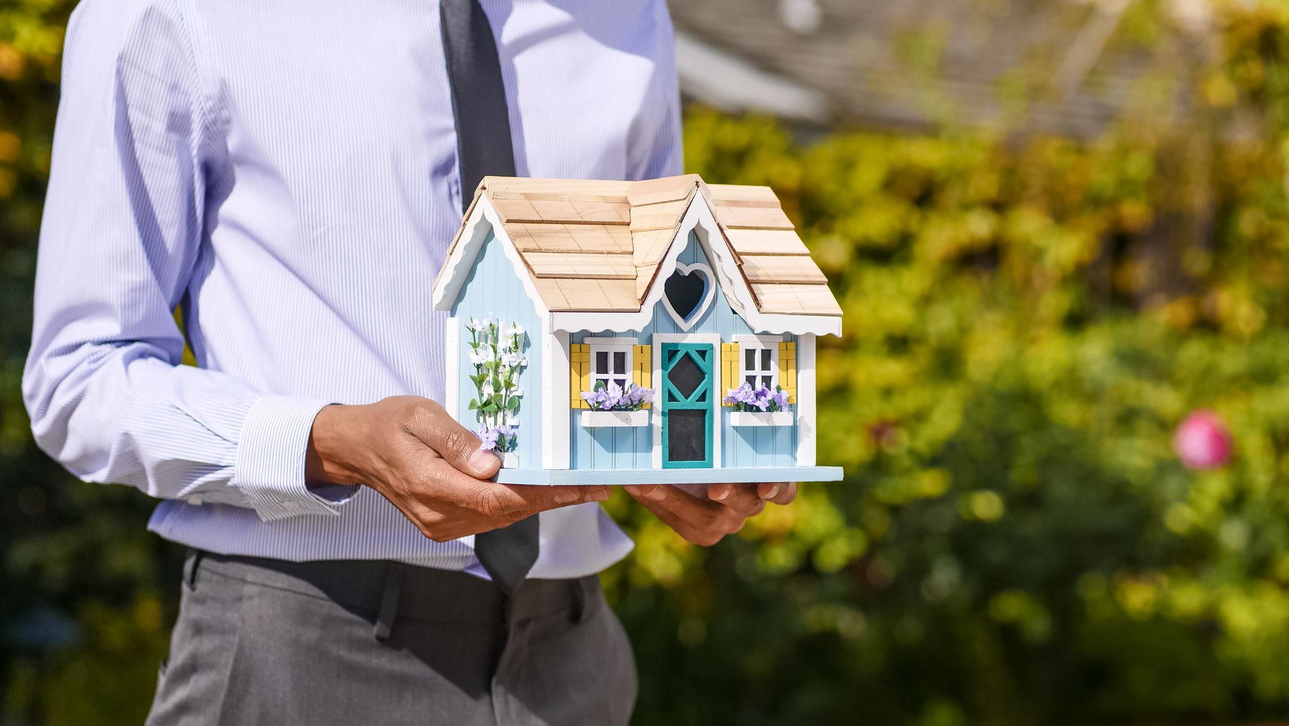 Homme tenant une maquette de maison miniature