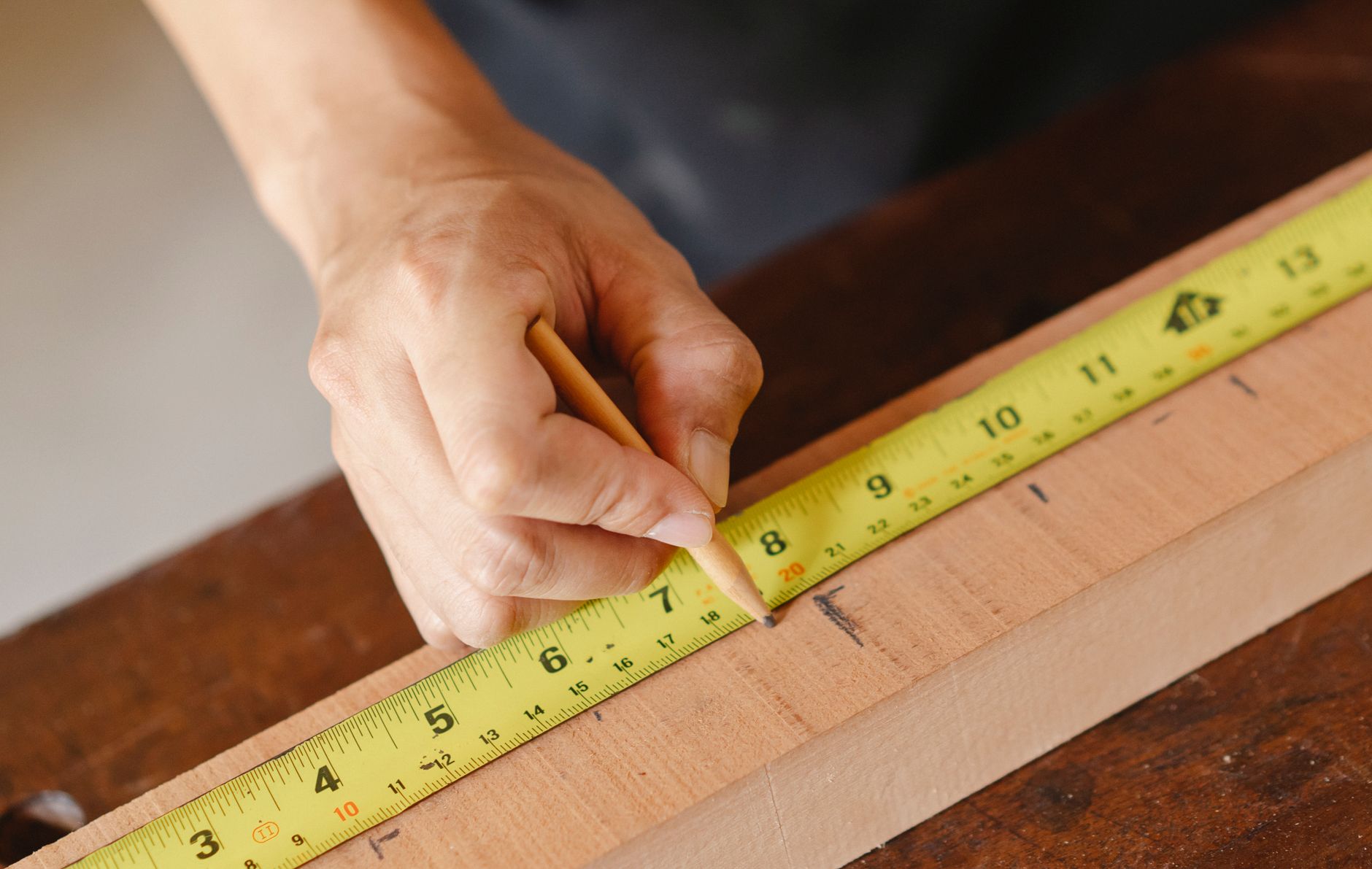 Artisan qui mesure une planche de bois avant la pose