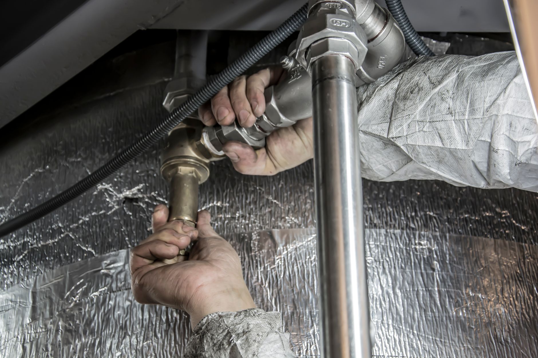 Mains qui installent des tuyaux de plomberie pour un chauffe-eau