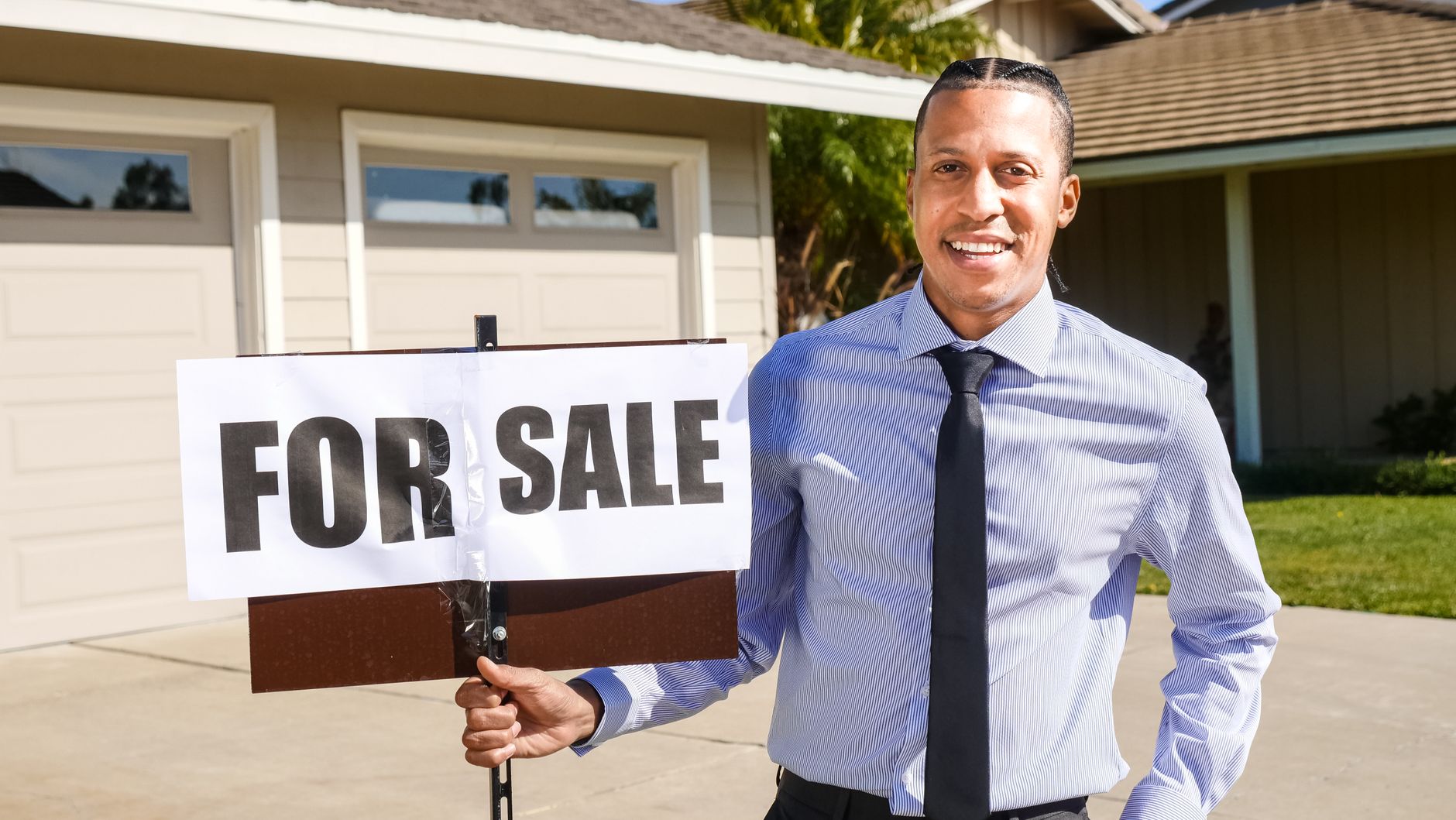 Agent immobilier devant un panneau a vendre