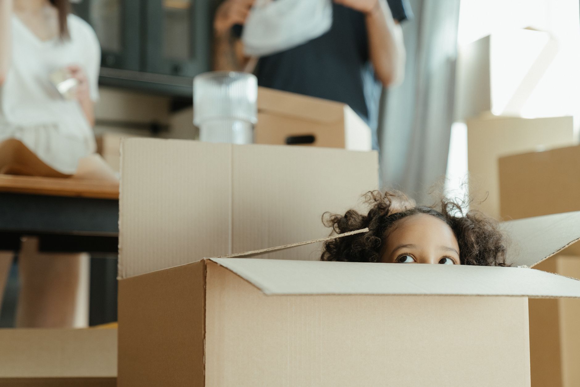 Enfant qui sort la tete d un carton de demenagement
