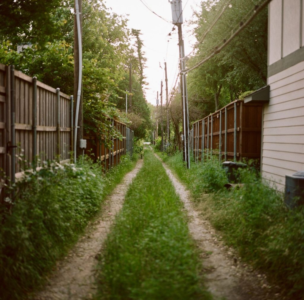 Ruelle bordée de clôtures entre deux maisons voisines