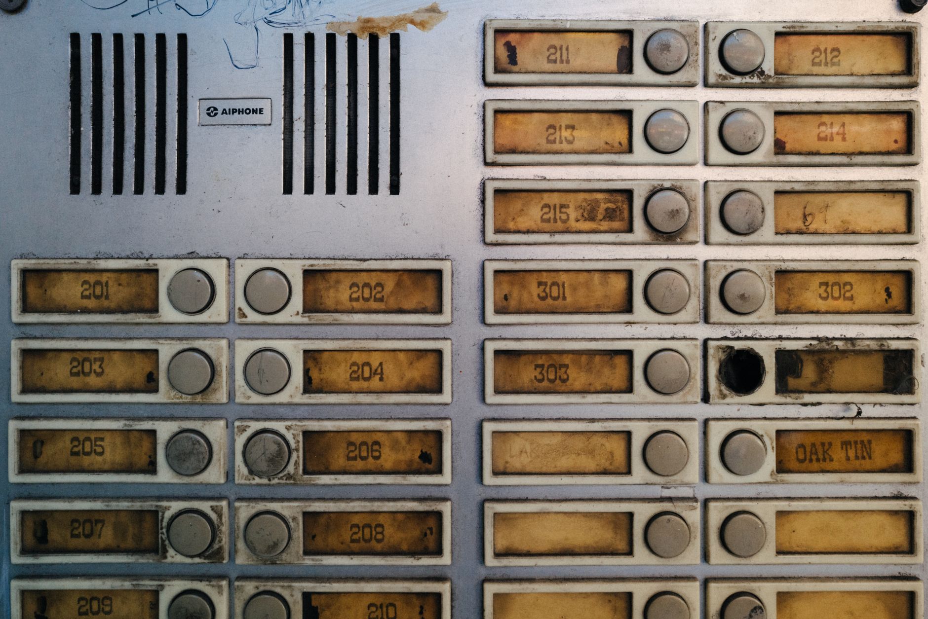 Ancien interphone d’immeuble usé près de la porte