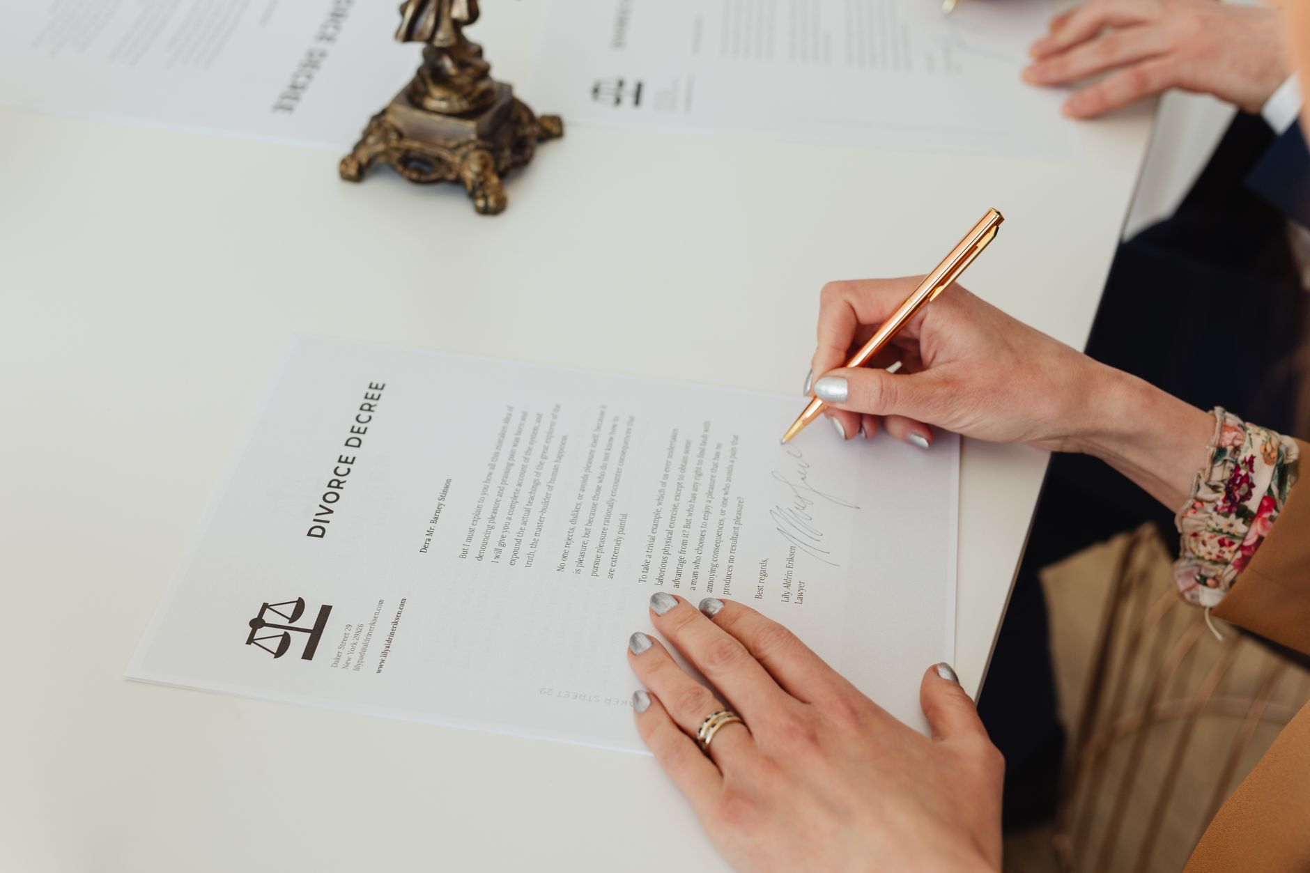 Mains qui signent un acte posé sur un bureau